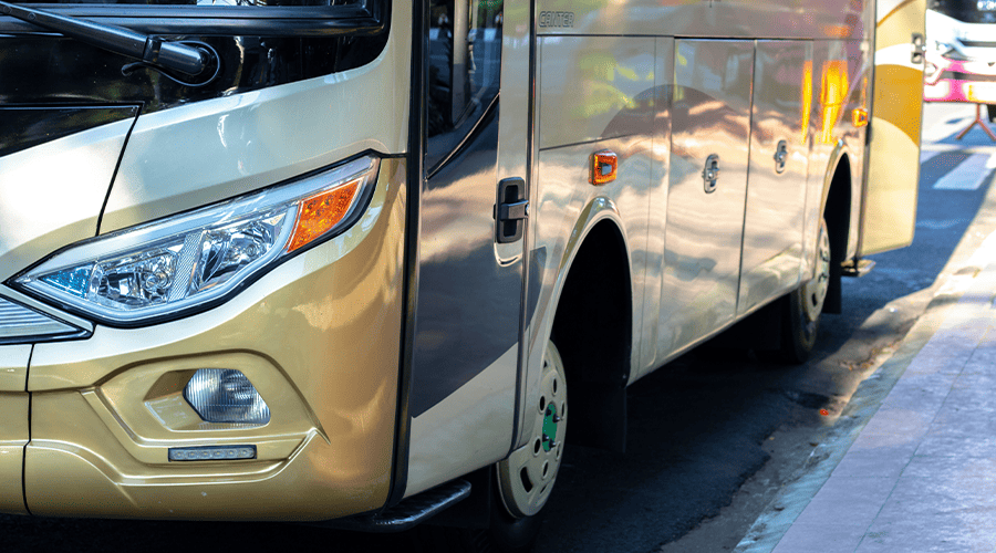 A gold and white airport bus showing two whells on its left side and the passenger door.