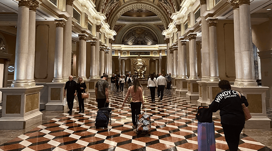 The Venetian Resort in Las Vegas with guests and visitors walking along a walkway with Venetian-inspired decor and guests pushing suitcases along the walkway.