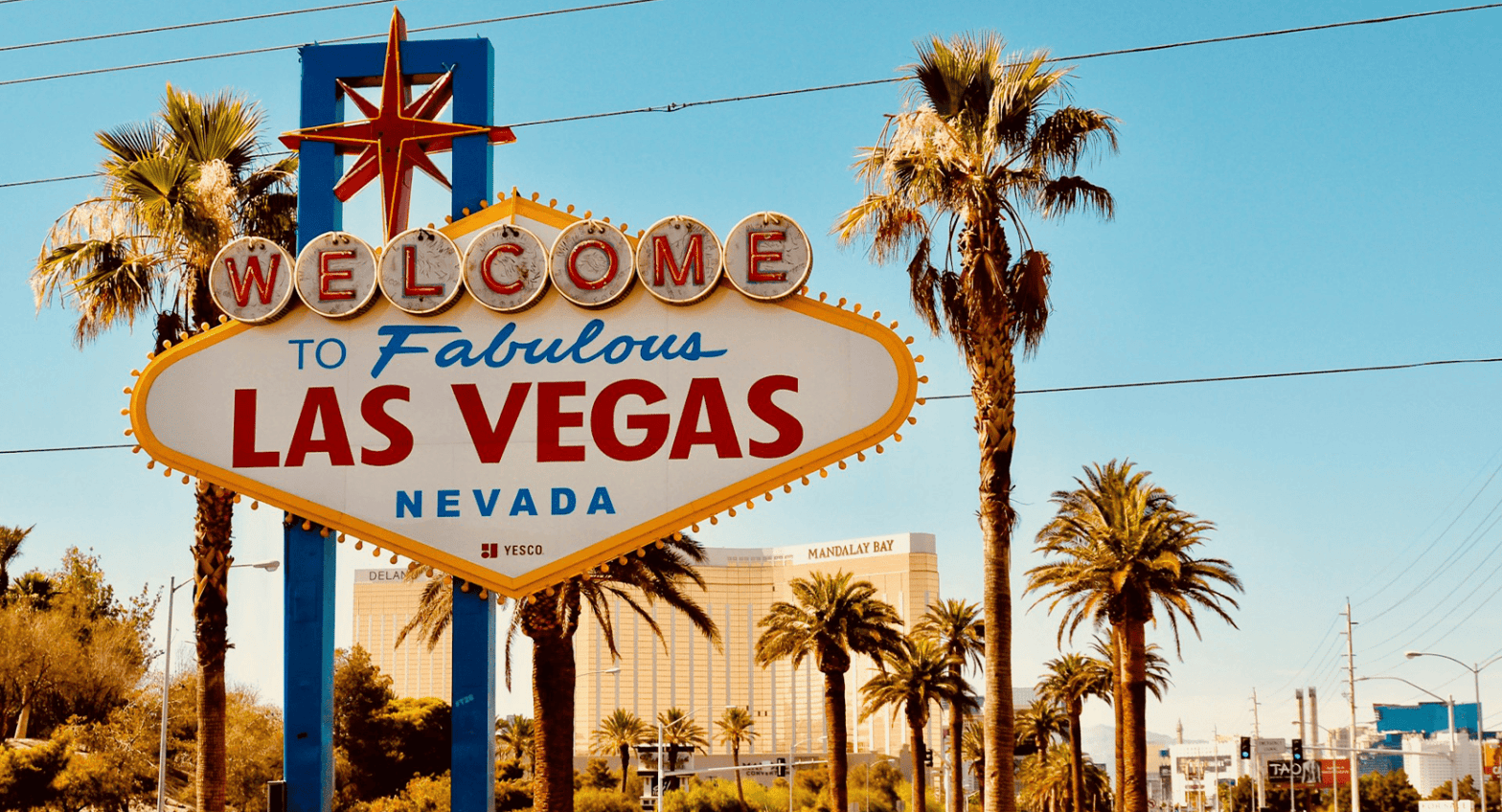 Iconic 'Welcome to Fabulous Las Vegas' sign with a bright blue sky and palm trees in the background, marking the entrance to the famous Las Vegas Strip.