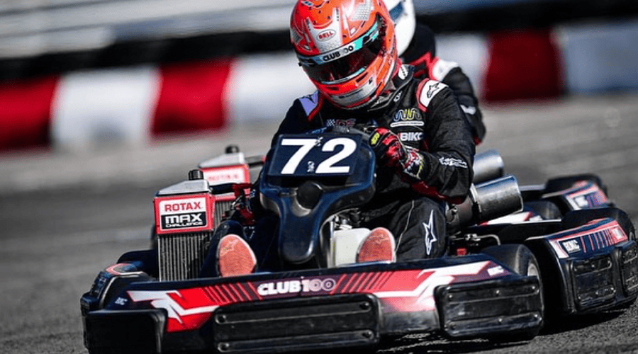 A person on a go-kart racing track wearing a white and white helmet and holding the steering wheel of a red and black go-kart at Llandow Circuit in Llantwit Major.