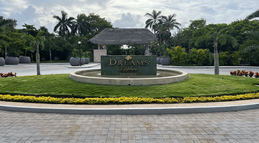 The Dreams Sapphire Resort & Spa entrance sign and landscaped grounds with palm trees and tropical gardens at the all-inclusive Mexico Caribbean resort.